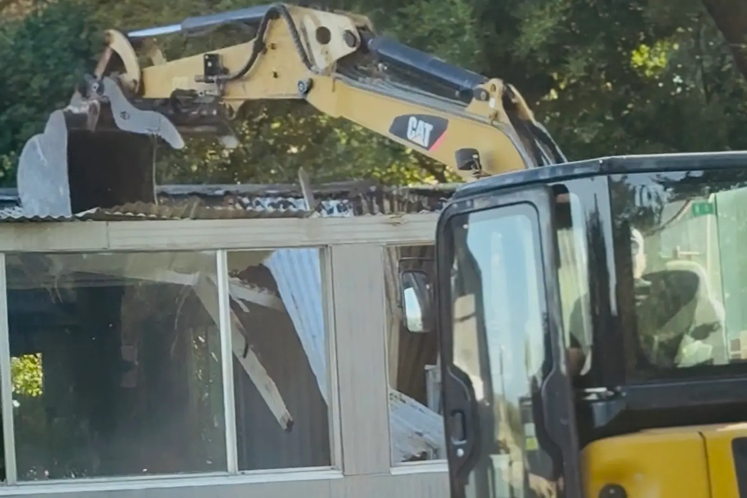 Mini excavator demolishing a shed