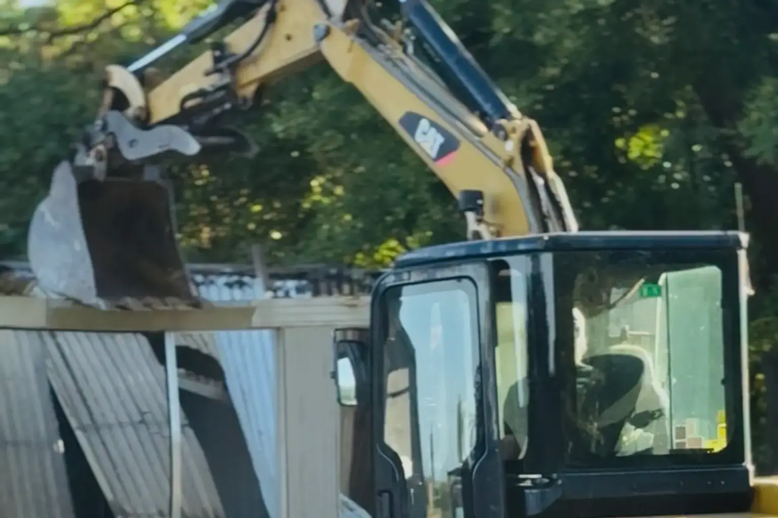 Mini excavator tearing down a roof during demolition